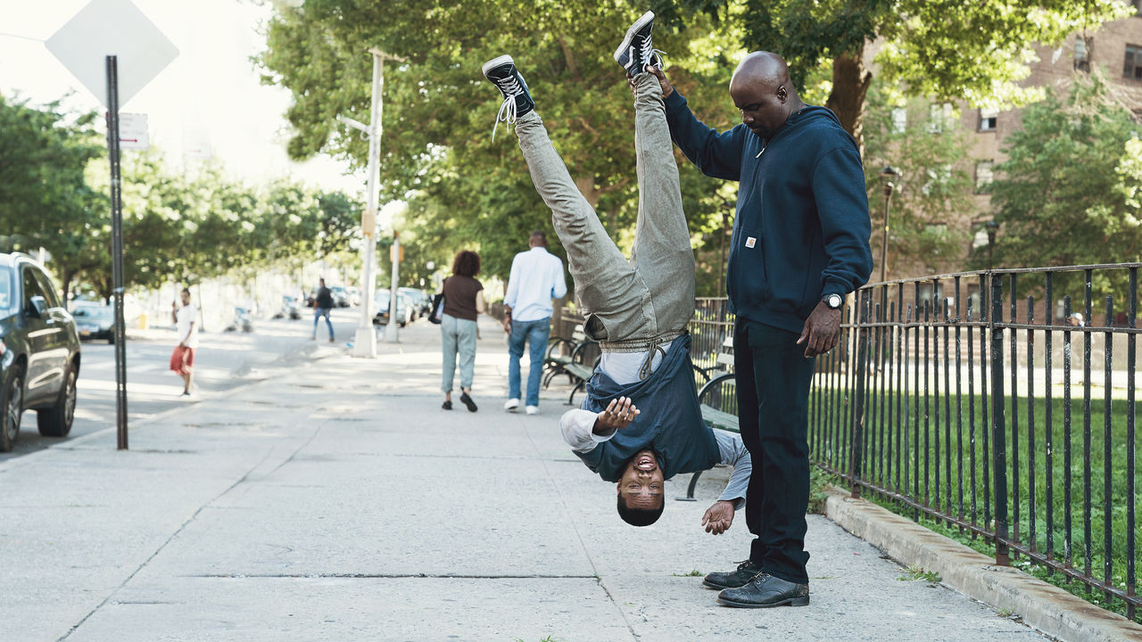 A scene from Netflix and Marvel's Luke Cage that shows one man holding another upside-down.