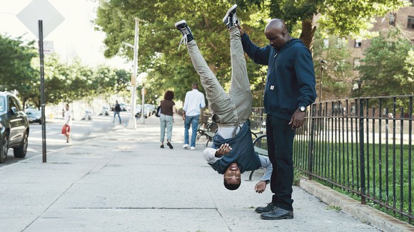 A scene from Netflix and Marvel's Luke Cage that shows one man holding another upside-down.