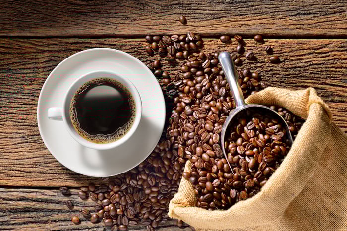 A coffee cup and coffee beans on a table.