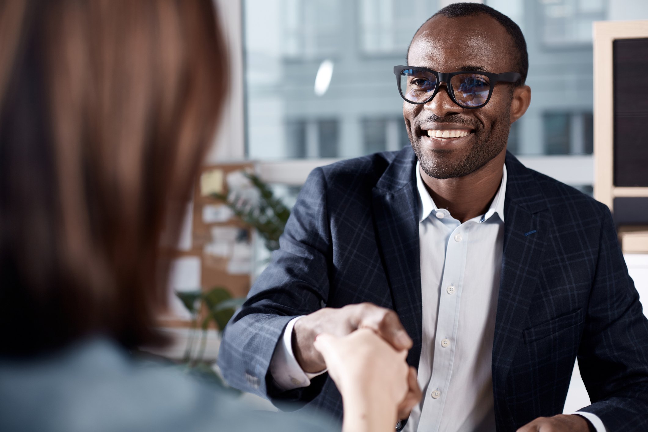 Smiling professionally dressed man shaking hands with woman.