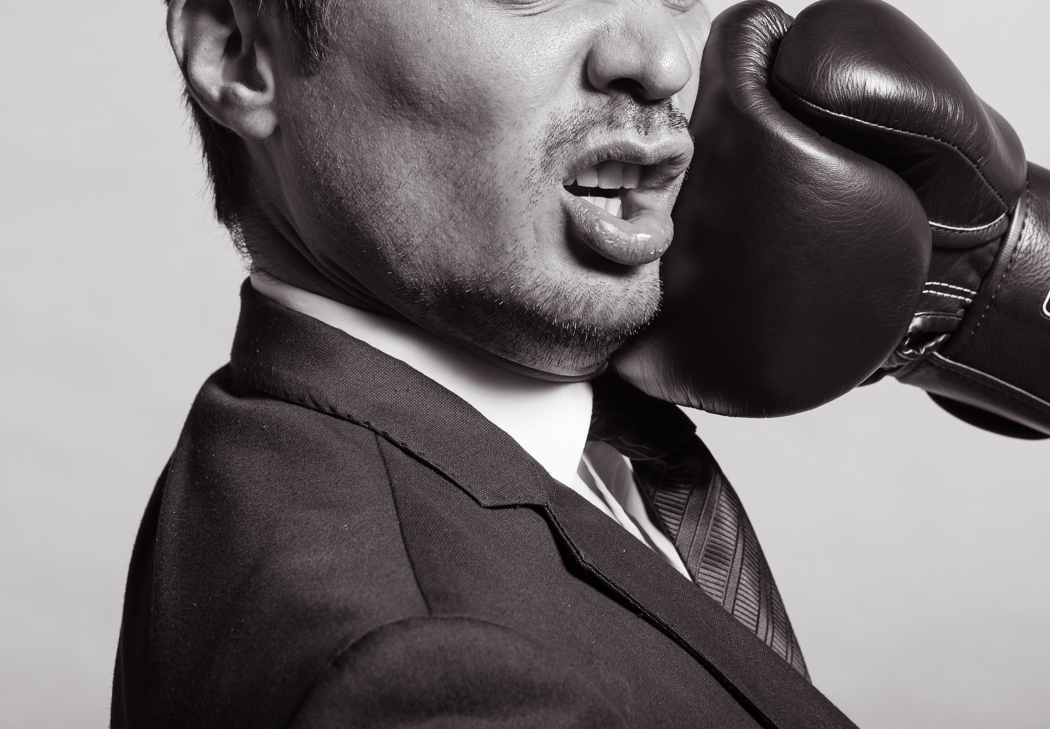 Businessman being punched in the face by a glove