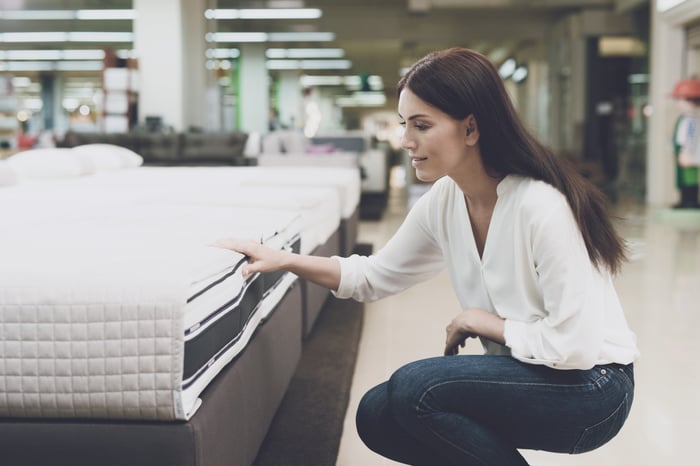 A woman touching a mattress in a mattress store.