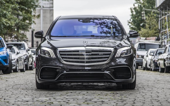 A black Mercedes-Benz S-Class sedan on a cobblestone street