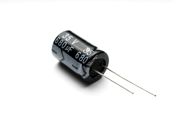 Close-up shot of a standard capacitor, rated at 680 uf, against a plain white backdrop.