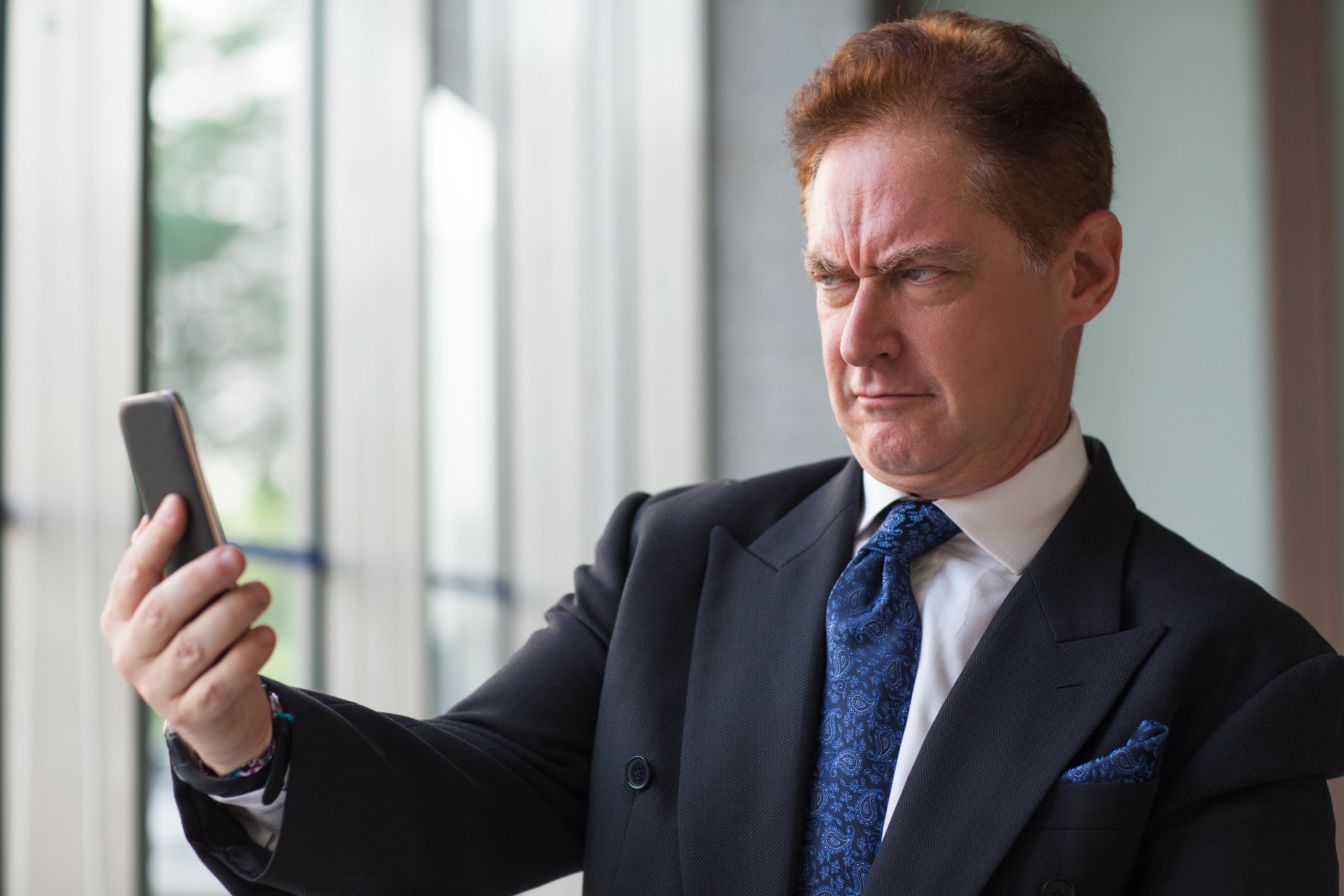 Man in suit scowling at his phone