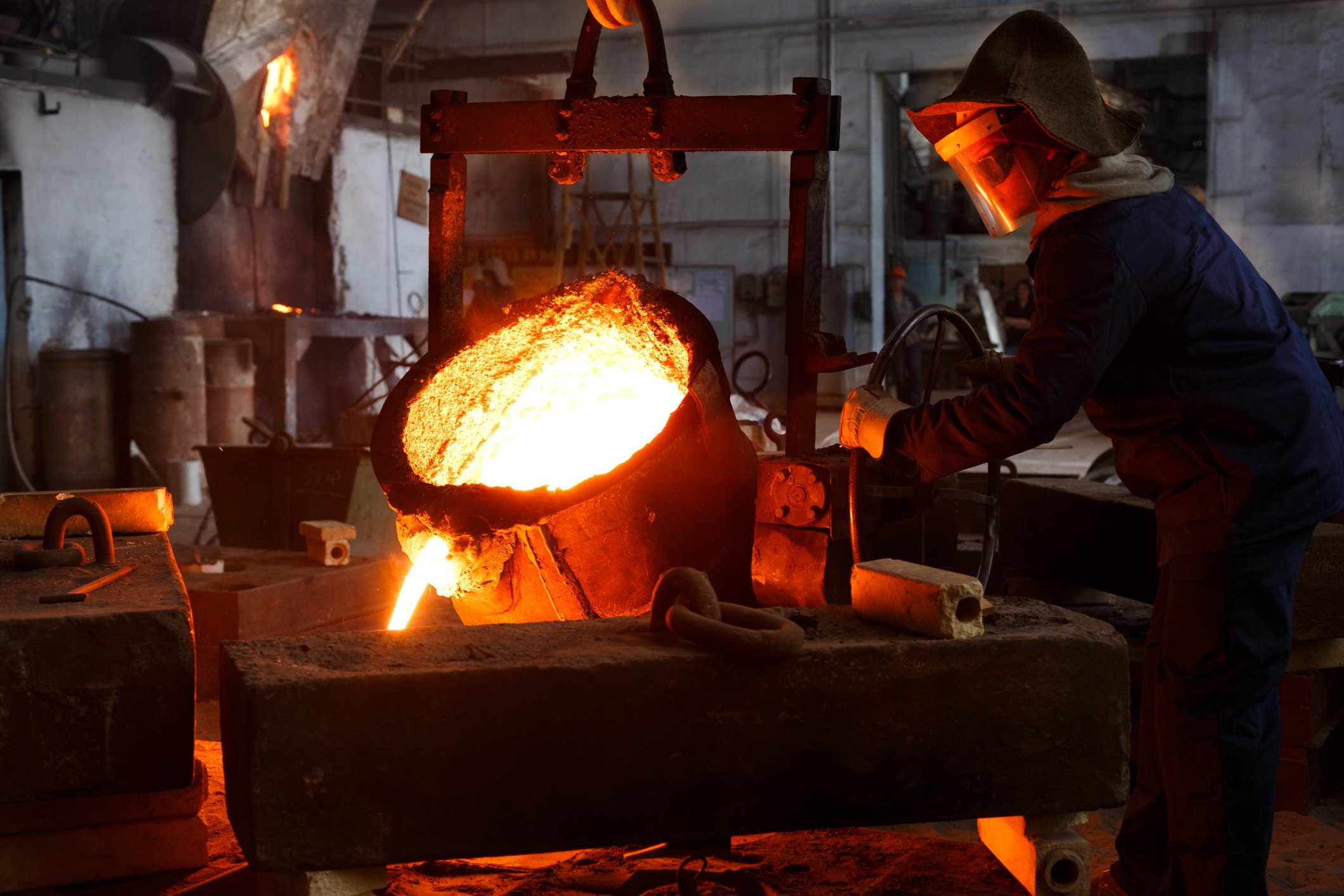 Worker pouring molten metal. 