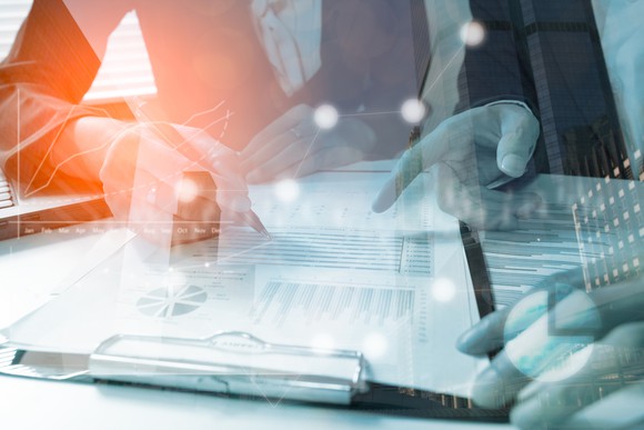 TWo business people looking at clipboard with numbers on it