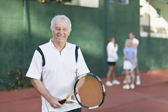 Senior man holding tennis racket.