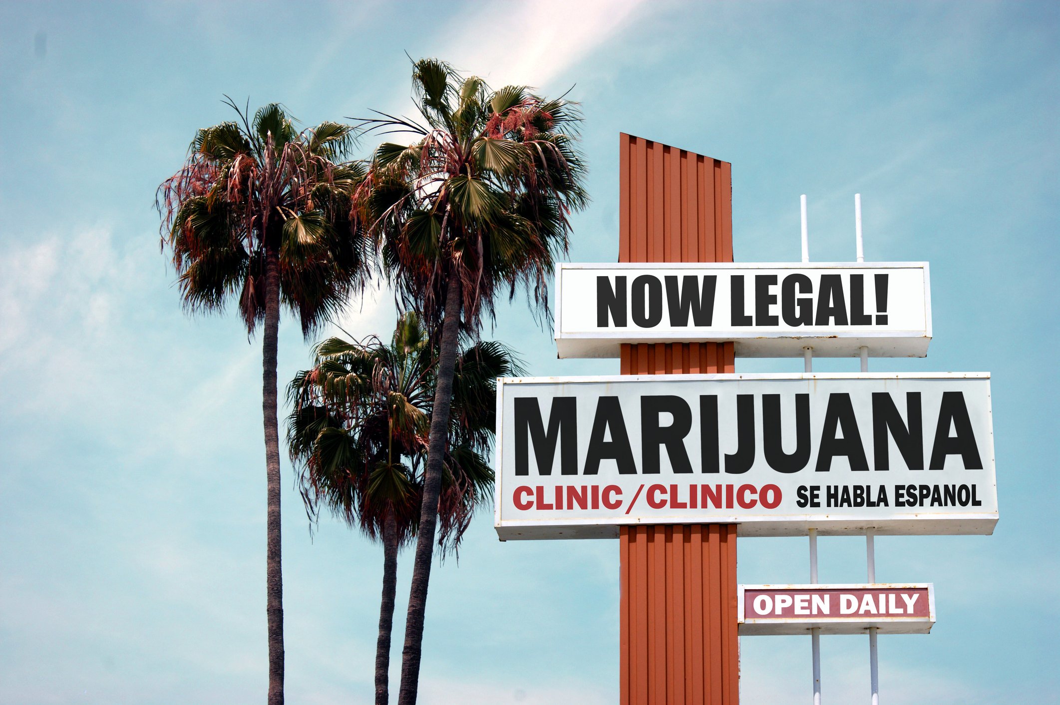 A sign for a marijuana store next to palm trees