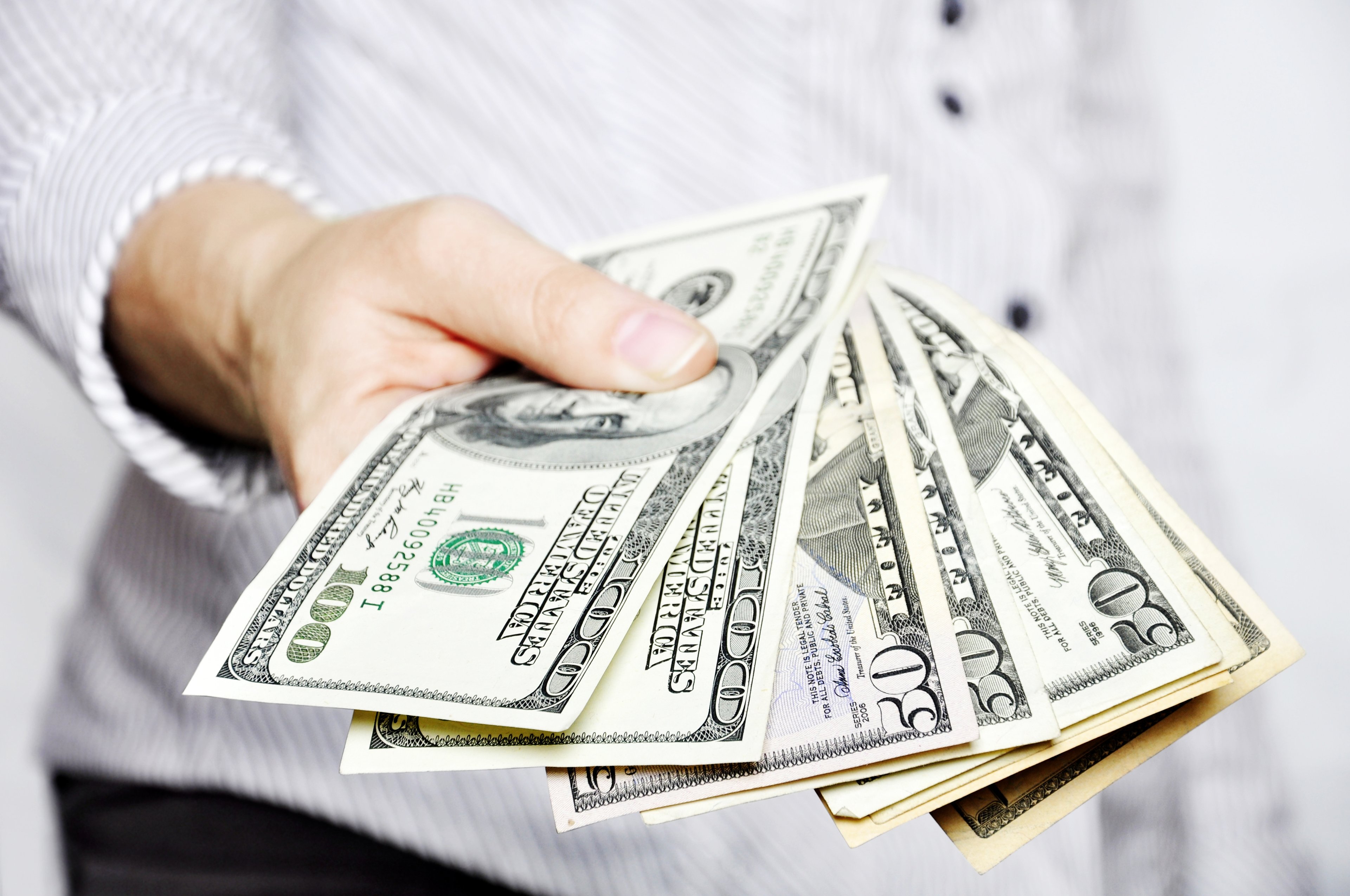 Man holding bills fanned out in front of him