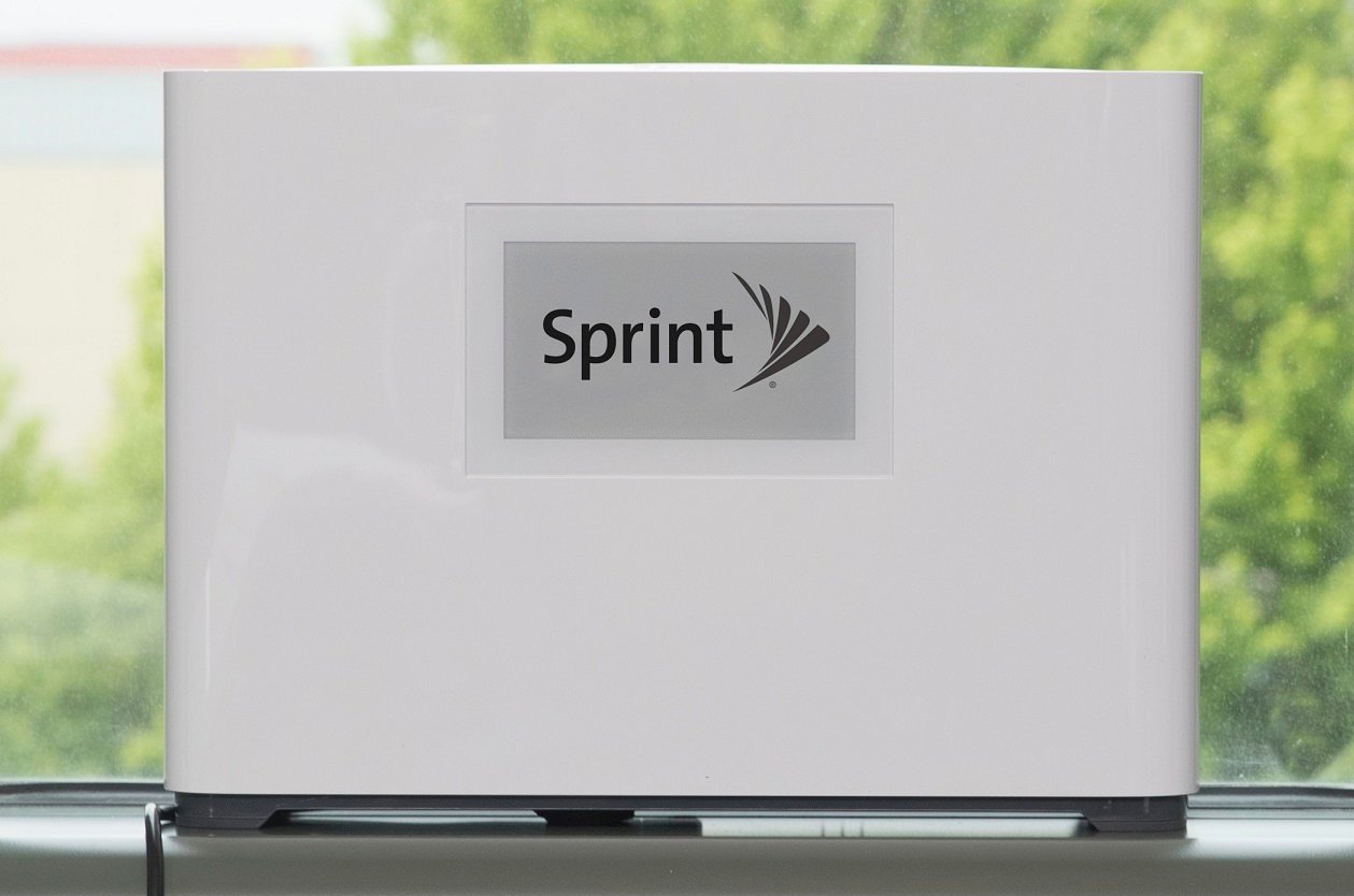 Laptop with Sprint logo on it, in front of a window showing green shrubbery.