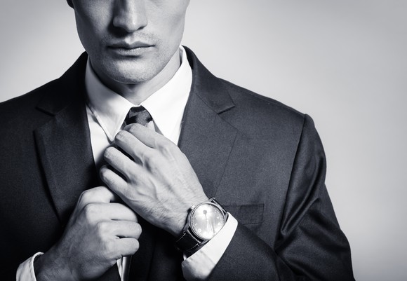 Image of a man in a suit fixing his tie.