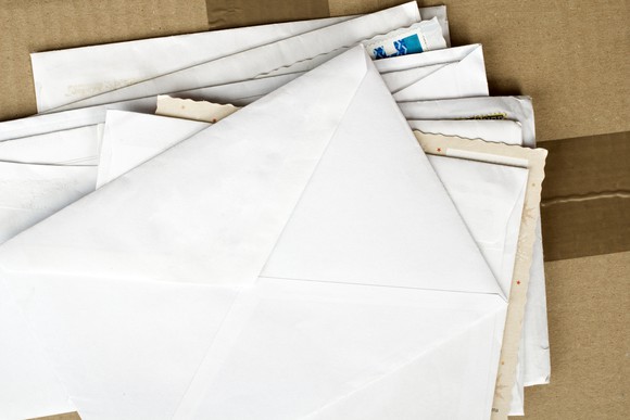 Bird's-eye view of a stack of envelopes on top of a cardboard shipping box.