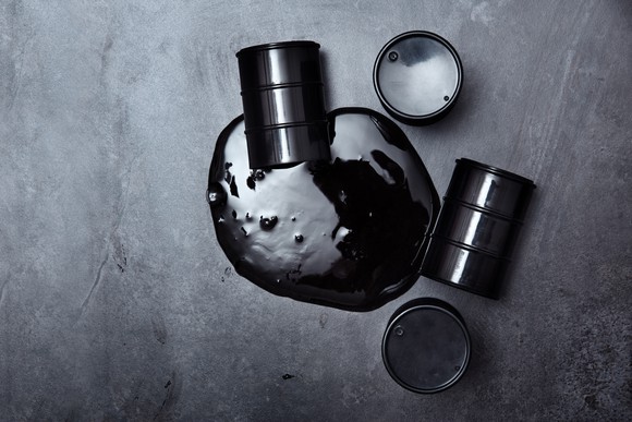 Oil drums surround a puddle of spilled oil.