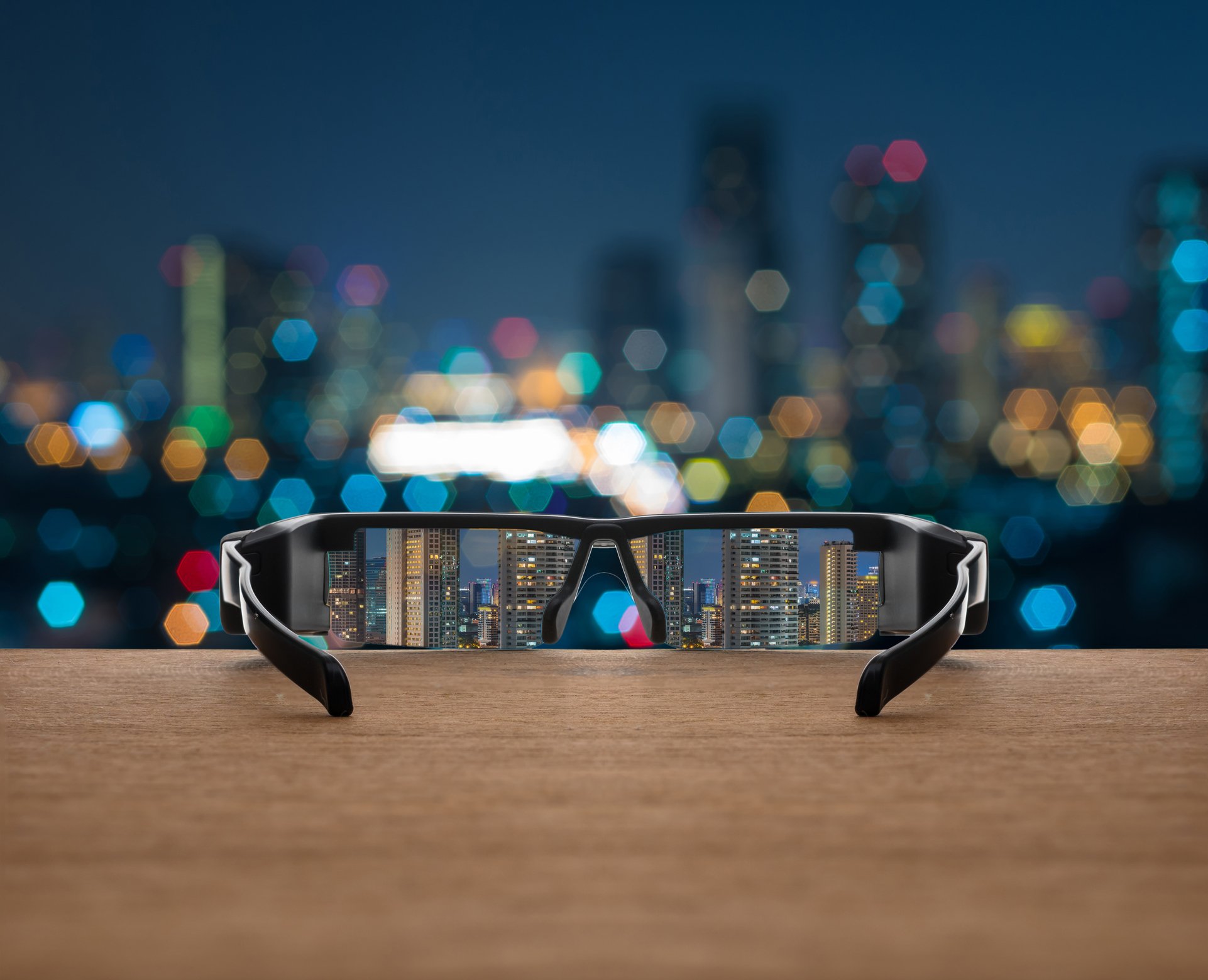 Augmented reality glasses sitting on a table, facing a night cityscape