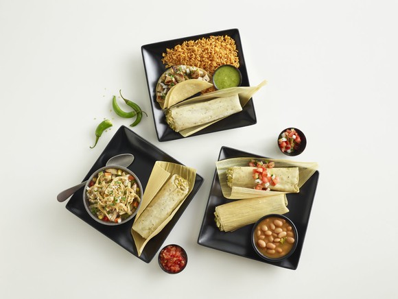 Three platters of El Pollo Loco's tamale special on black plates.