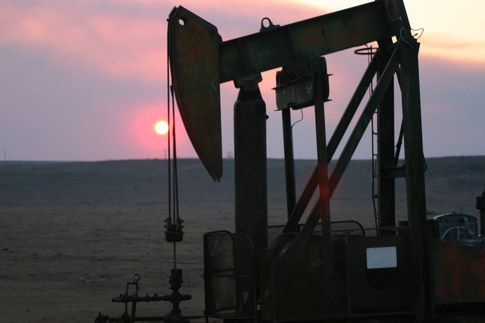 An oil pump with the sun setting in the background.