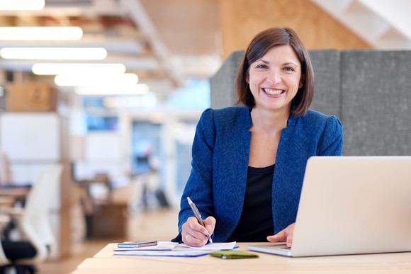 Woman smiling while working on a laptop