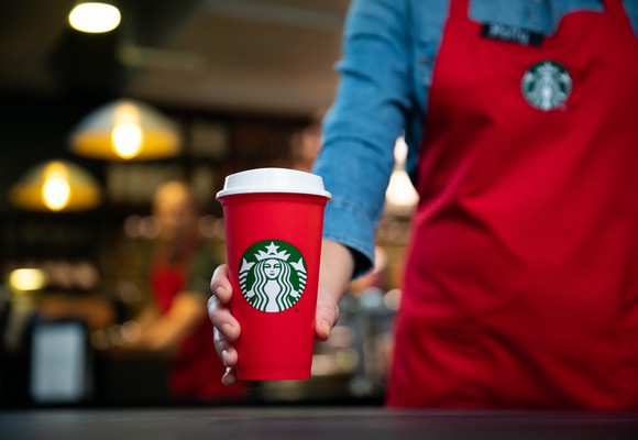 A barista holds a Starbucks holiday cup.