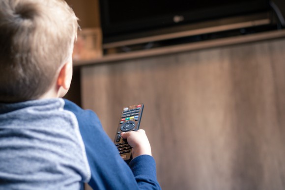 A young boy holding a TV remote.