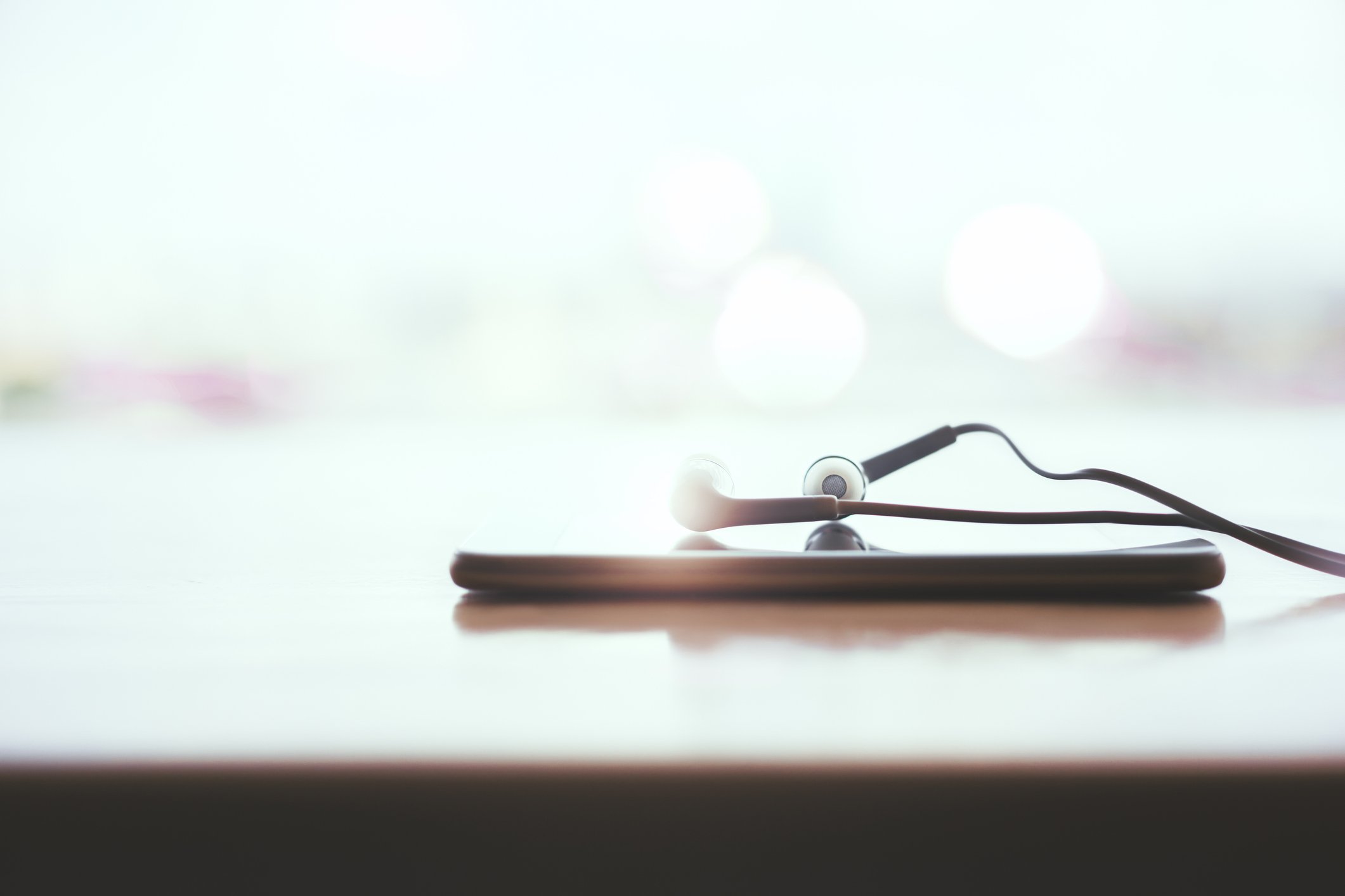 Earbud headphones on top of a mobile phone.