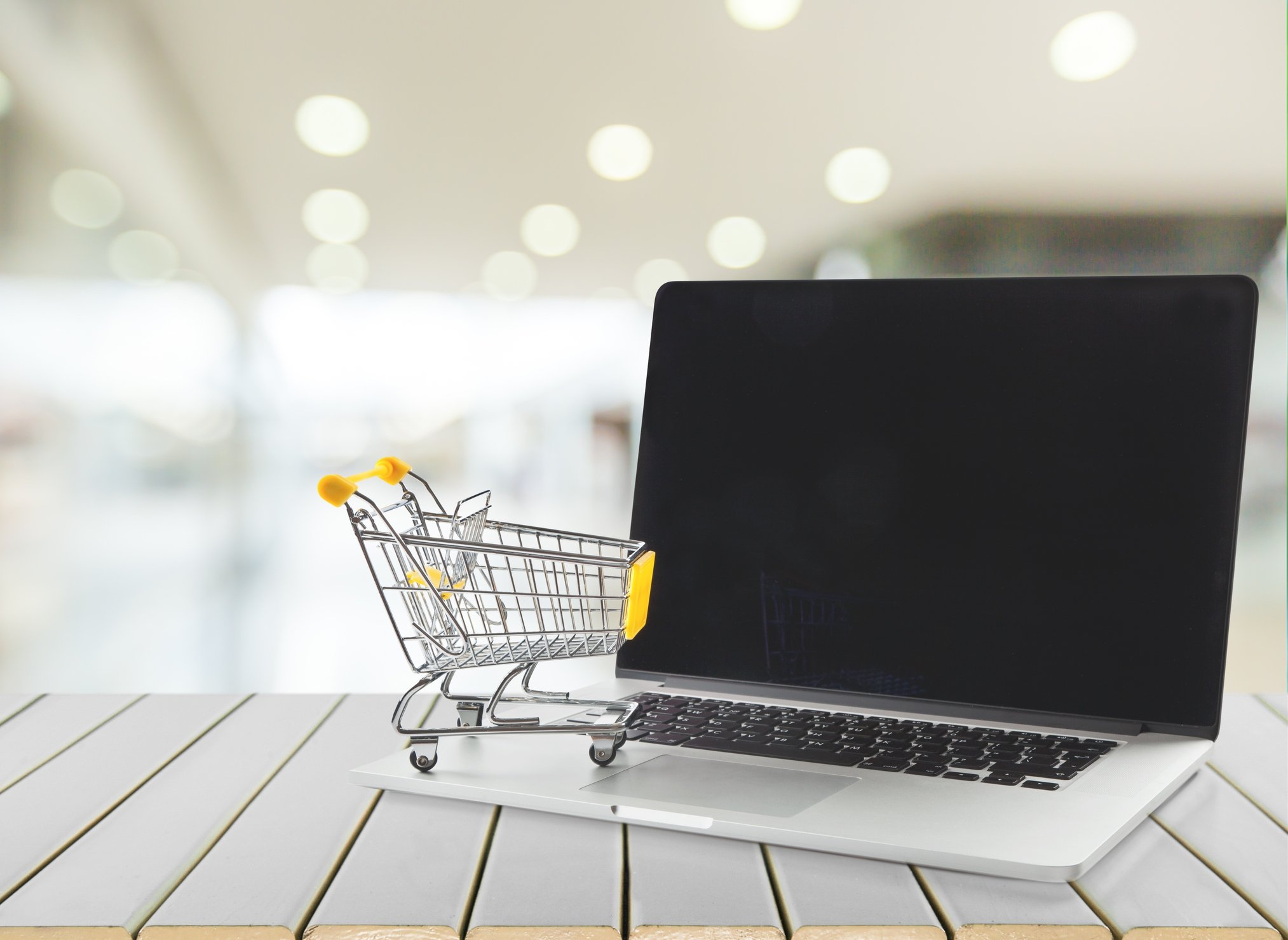 A miniature shopping cart on top of a laptop.