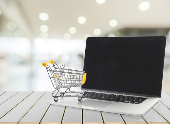A miniature shopping cart on top of a laptop.
