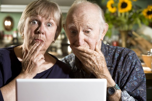 A senior couple surprised by what they're seeing on a laptop.