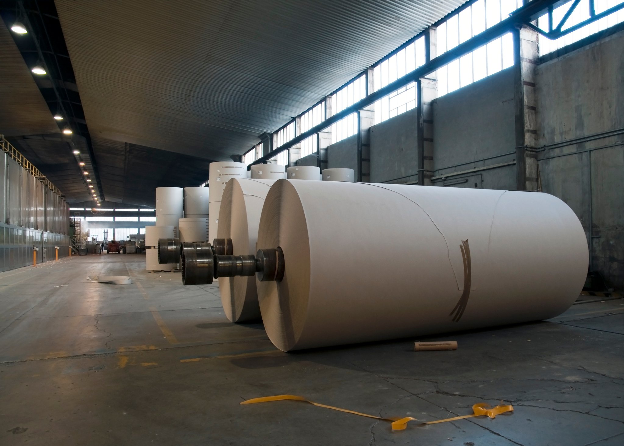 Giant paper rolls sit in a warehouse.