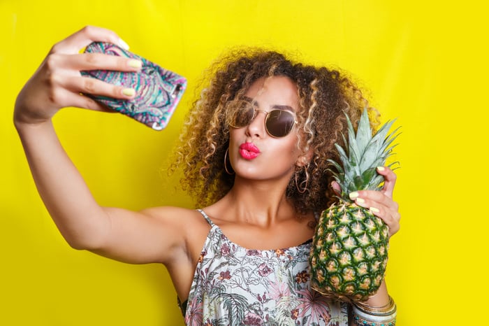 A woman takes a selfie with a pineapple.