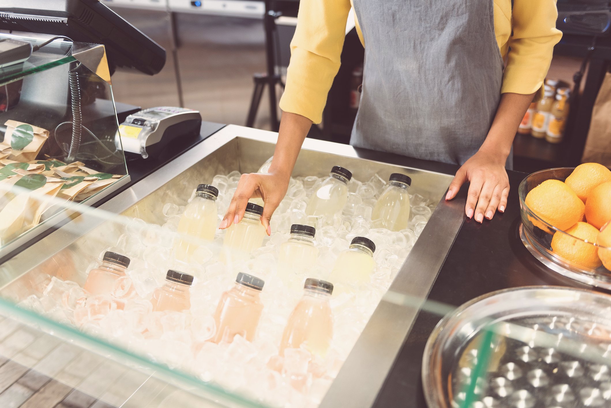 An employee arranges fresh fruit drinks in the "grab and go" section of an airport concessions store.