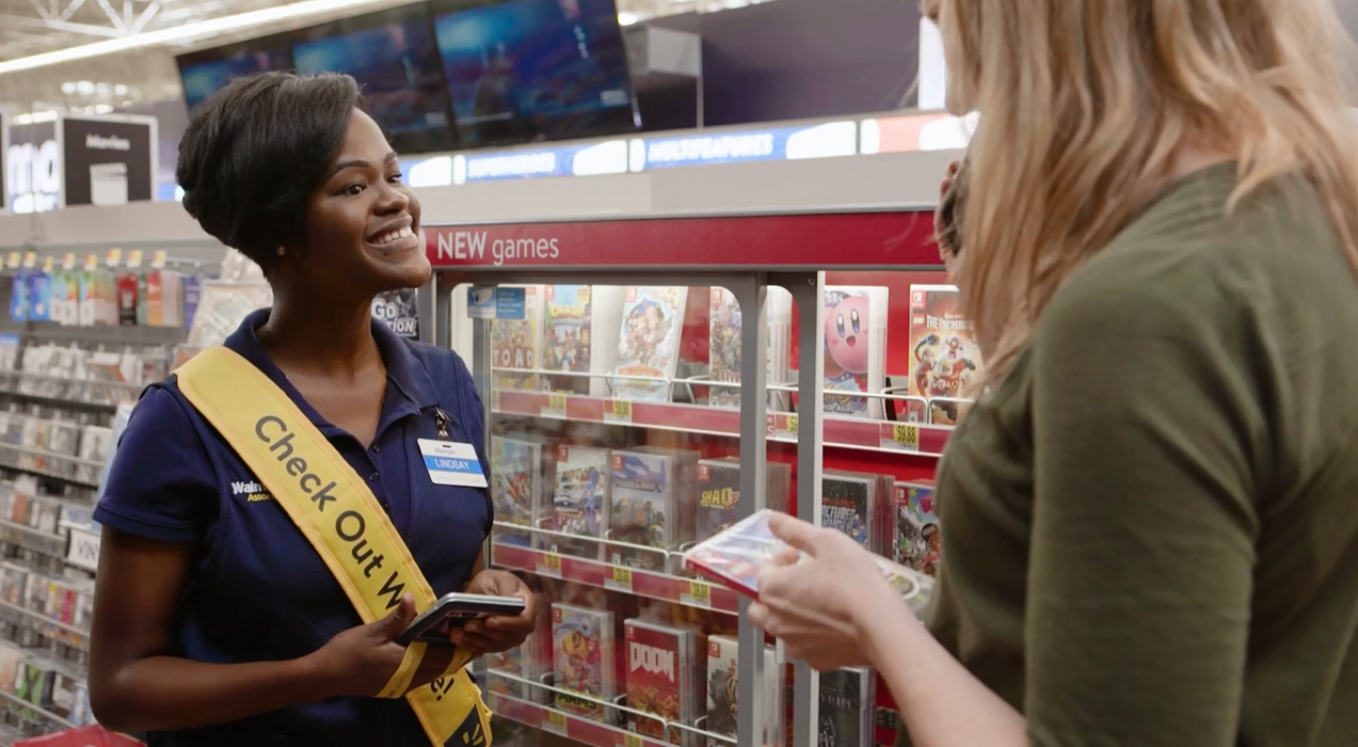 A Walmart employee helps a consumers with mobile checkout.