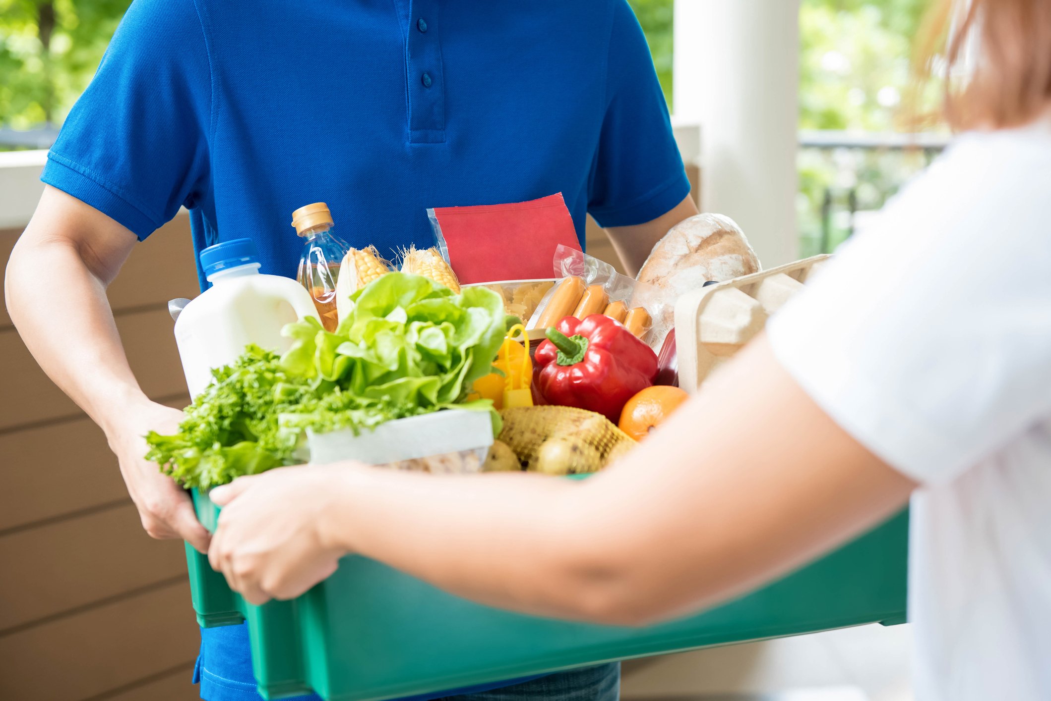 Man handing box of groceries to woman