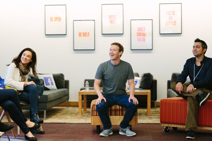 CEO Mark Zuckerberg sitting with three colleagues in an office, with all of them smiling.