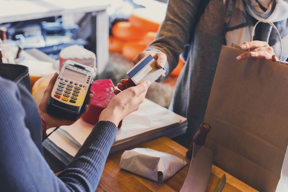 A customer hands a clerk a credit card to pay for a purchase.
