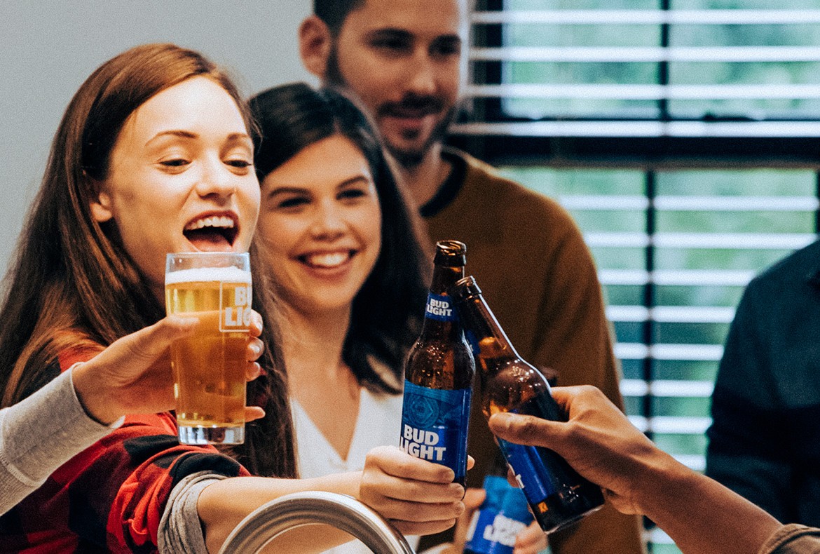 A group of young people toasting with bottles of Bud Light.