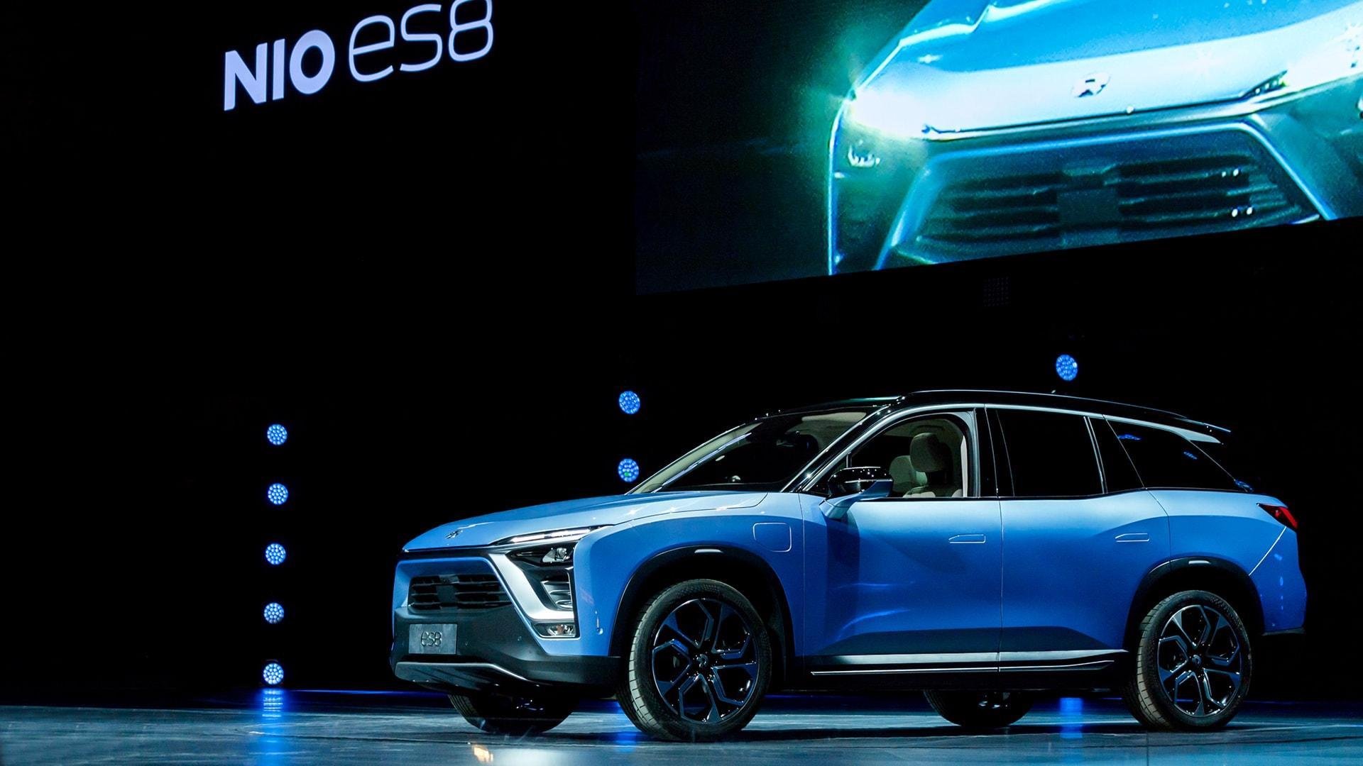 A blue NIO ES8, a midsize electric SUV, on an auto-show stage. 