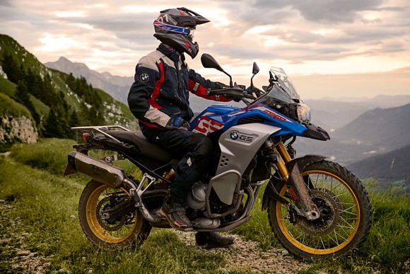 A BMW F 850 GS Adventure, a motorcycle designed for rugged terrain, is shown with a rider in a mountain setting.