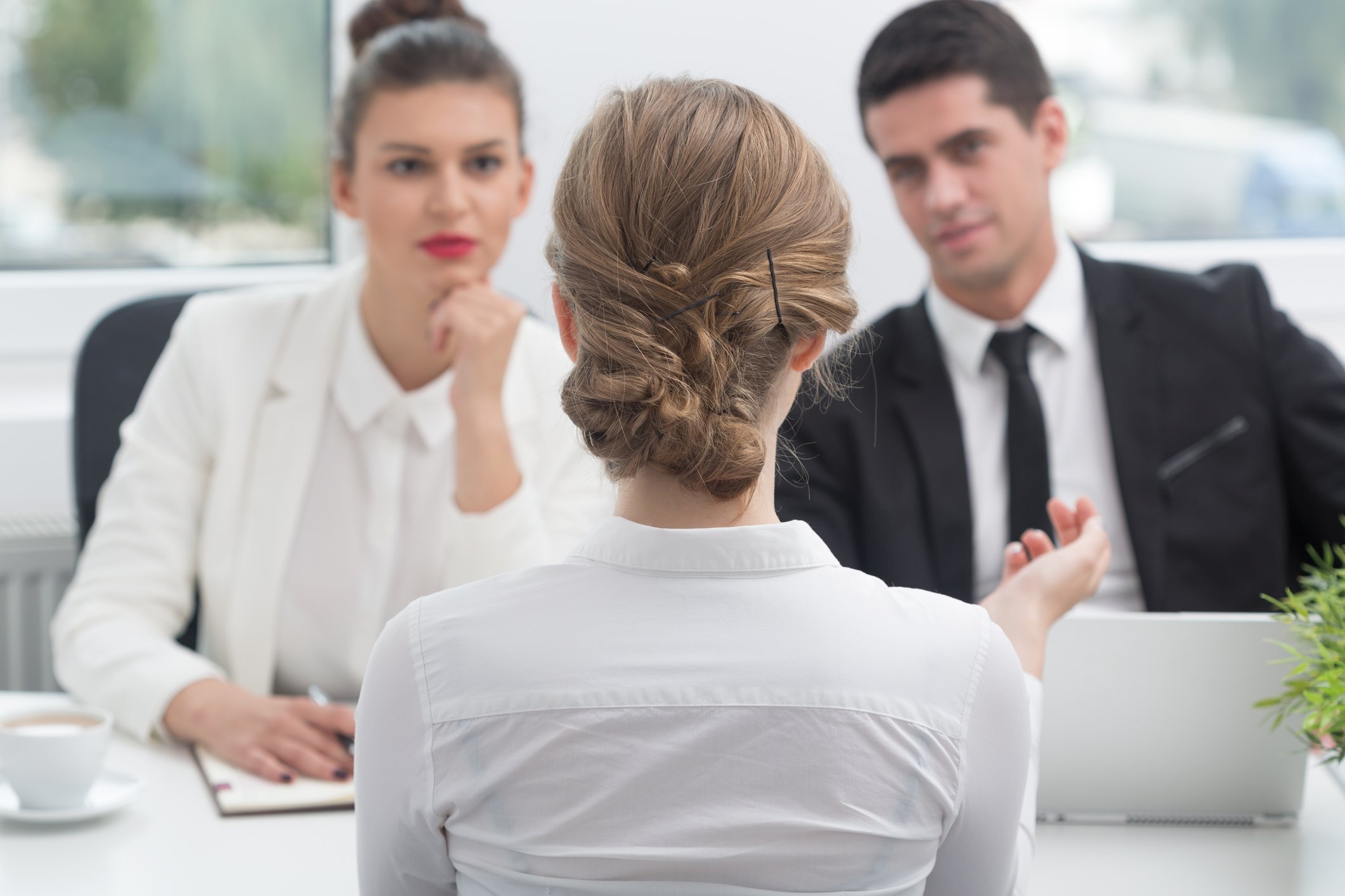 Well-dressed people sit acroos from each at a table.