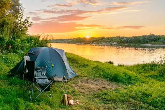 Image of a tent set up with lake in the background.