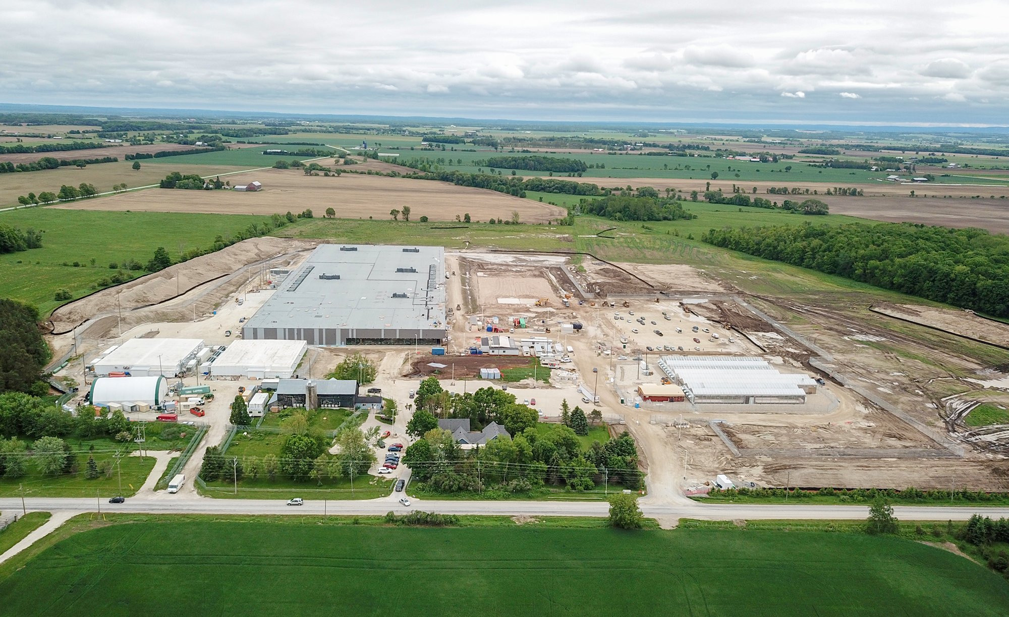 Aerial view of industrial facility under construction, with one building complete and several other footprints being worked on.