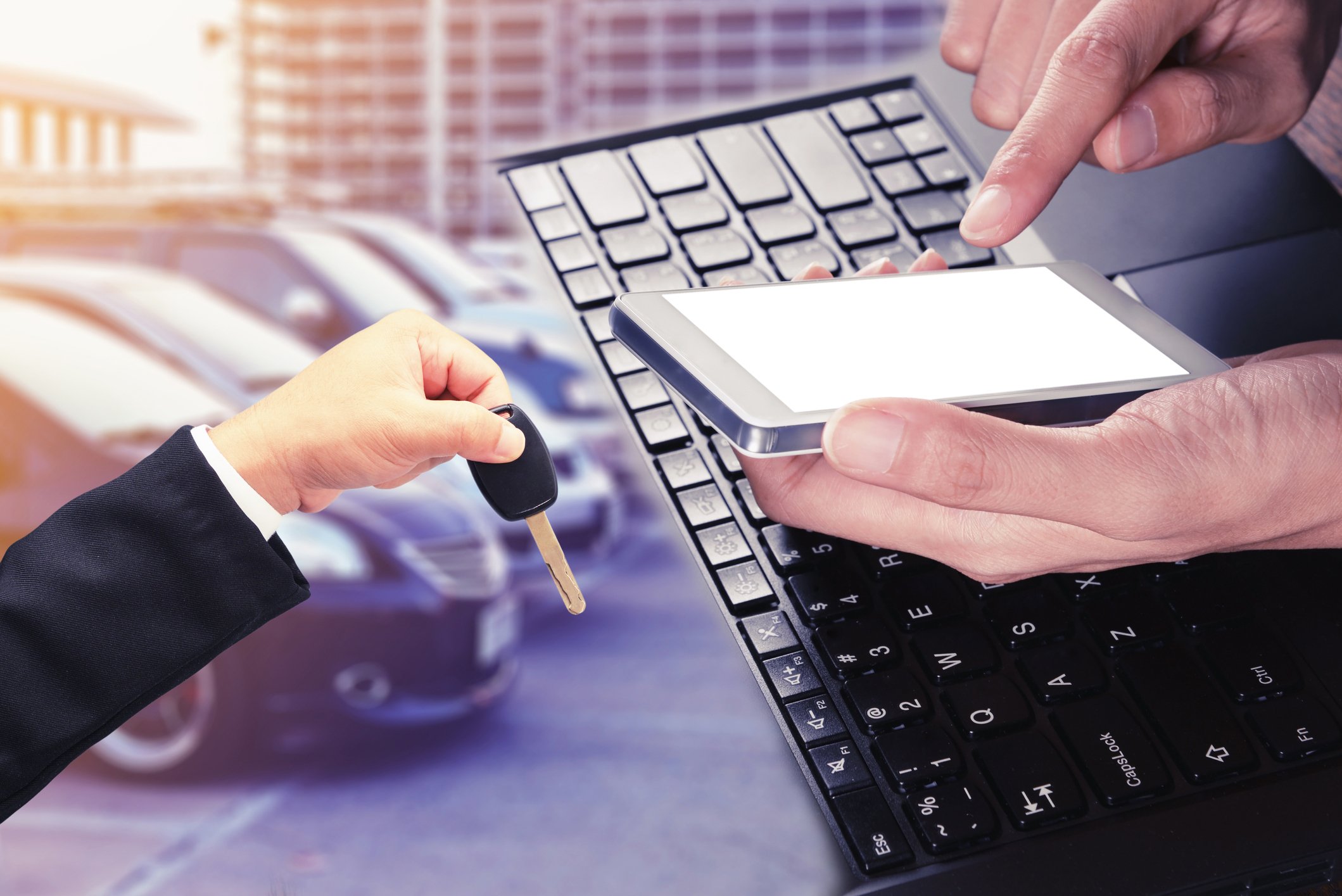 Image of man on mobile phone with keys and cars in the background.