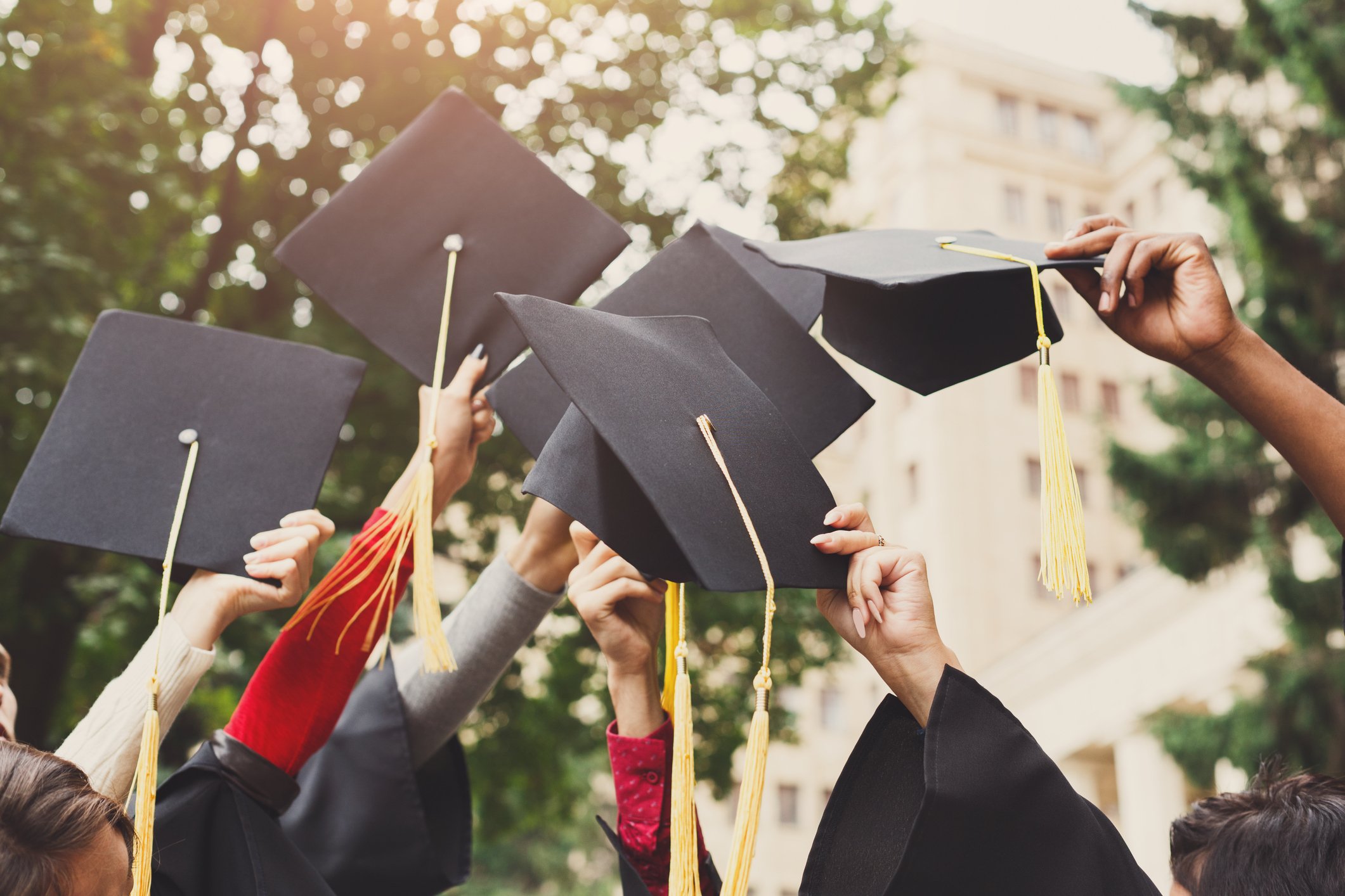 Graduating students lifting their caps into the air.