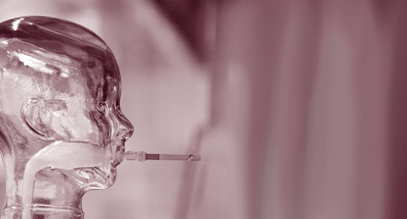 Glass sculpture of head with cigarette in its mouth.