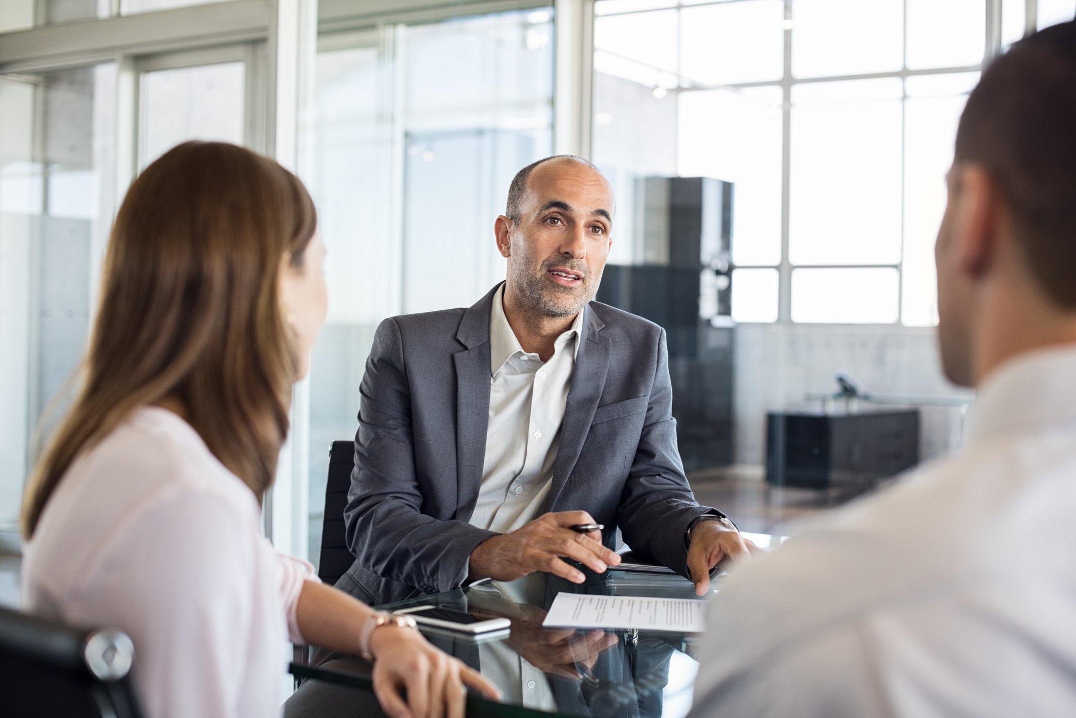 Man in suit talking to man and woman.