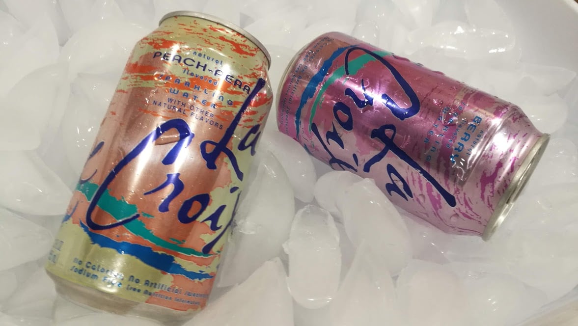 Two cans of LaCroix resting on a bed of ice cubes.