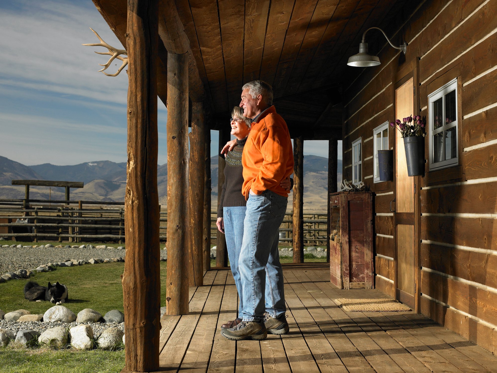 Older couple on porch of a home with a mountain view.