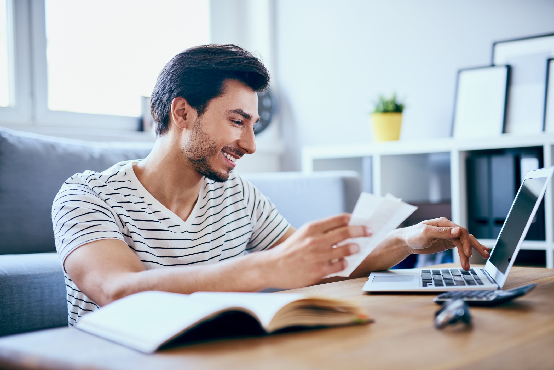 A person holding papers sits at a computer