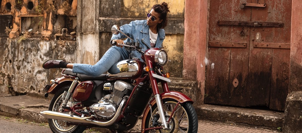 Woman climbing onto a Jawa motorcycle