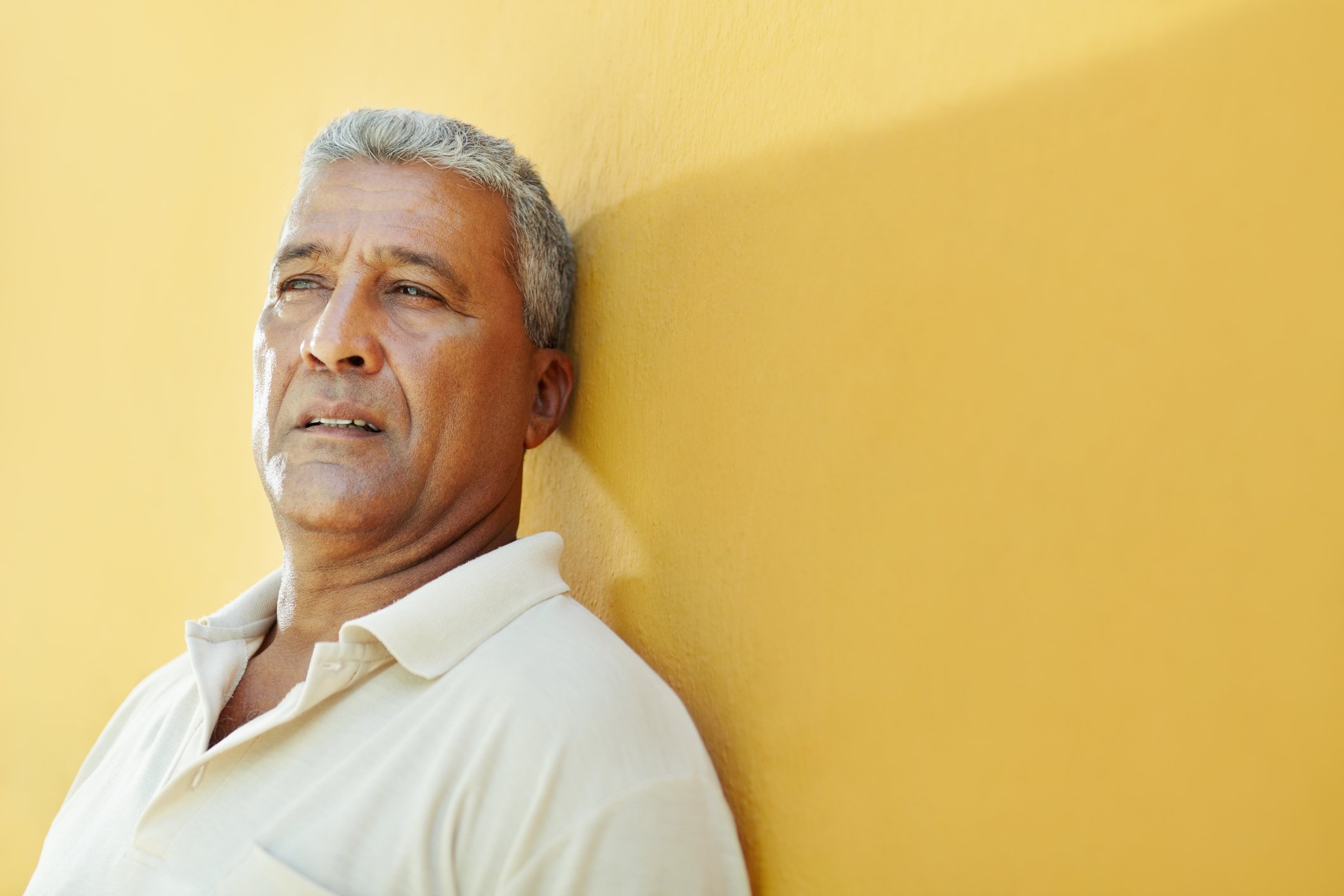 Older man with worried expression against a yellow background.
